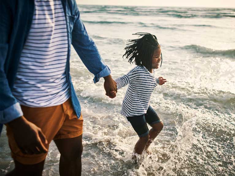 Child and man splashing in sea