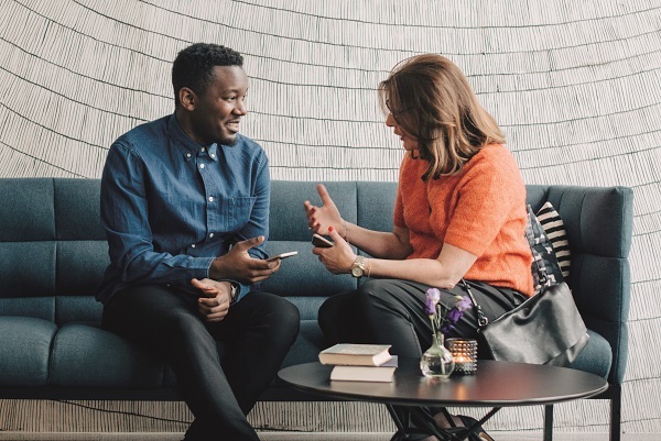 Two people sitting on a sofa in discussion