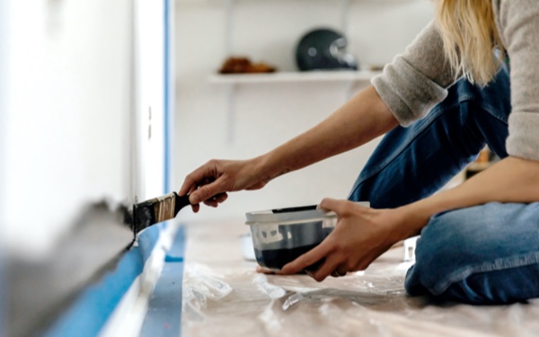Person painting wall above skirting board