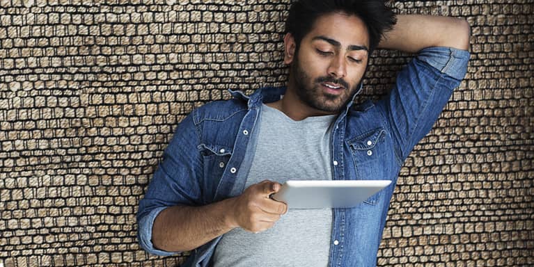 Young man laying down whilst looking at his ipad