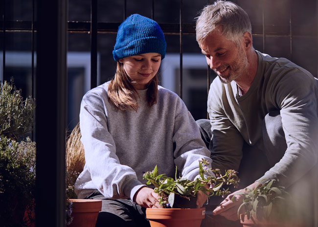 Man and girl tending pot plants.
